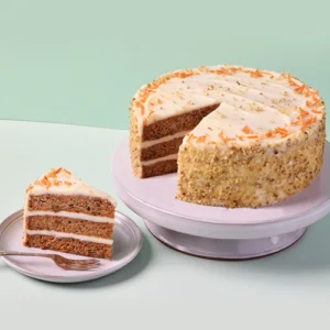 A Carrot Cake on a stand with a slice on a plate