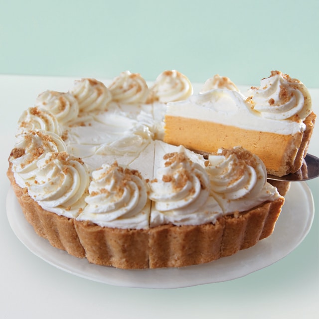 A pumpkin pie cheesecake on a plate with a slice being removed