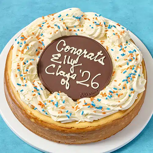 A decorated cheesecake with "Congrats Elly Class of 26" piped on top