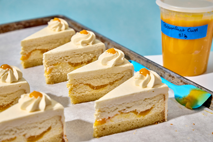 Slices of cake on a tray with a container of passion fruit curd