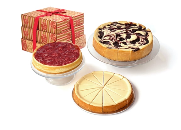 A display of three cheesecakes - Strawberry, Blueberry, and Original Plain