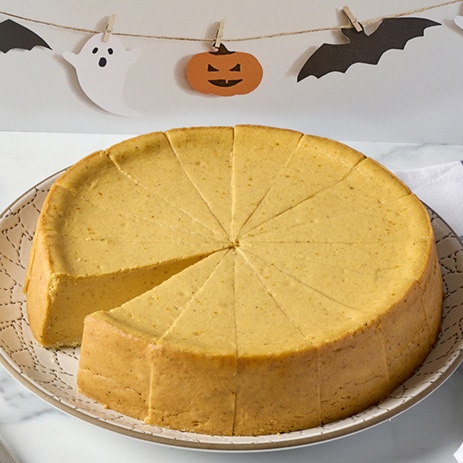 A pumpkin cheesecake with a Halloween banner in the background