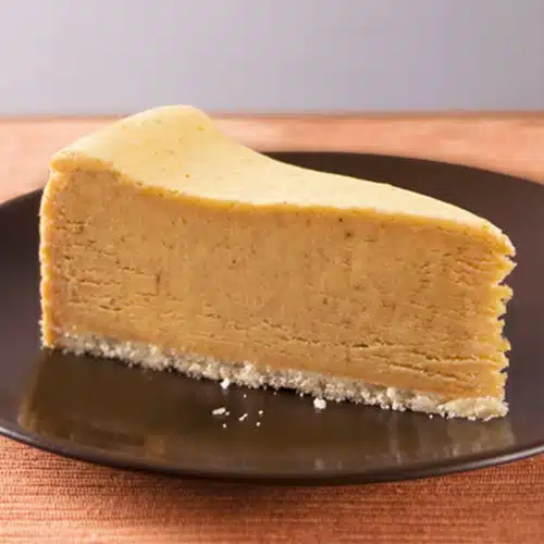 A slice of pumpkin cheesecake on a brown plate