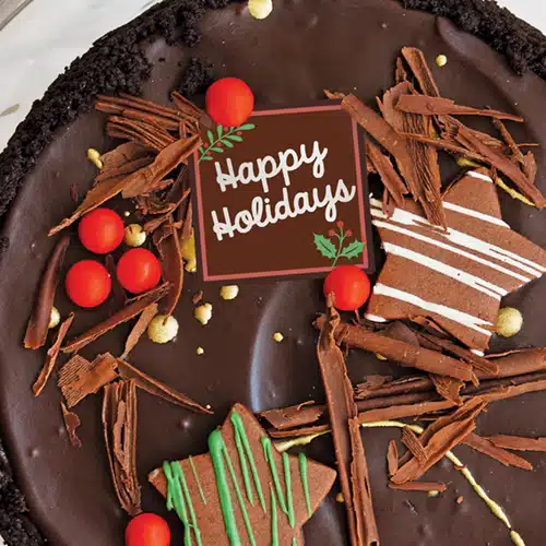 A chocolate cheesecake decorated with a Happy Holidays message.