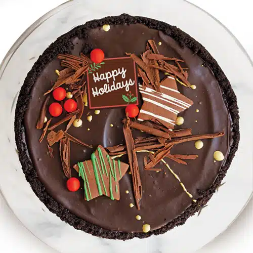 A chocolate cheesecake decorated with a Happy Holidays message.