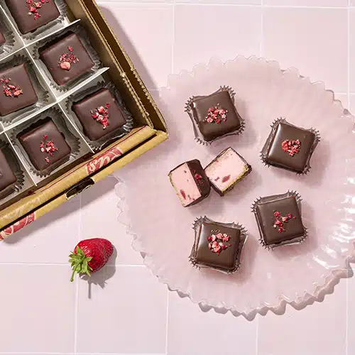 Bite-sized squares of strawberry cheesecake, dipped in chocolate