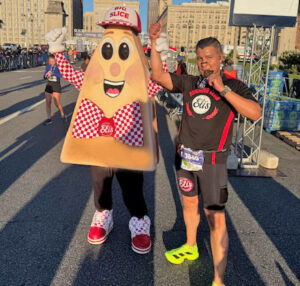 A runner poses with the Eli's Cheesecake slice mascot at Run Mag Mile